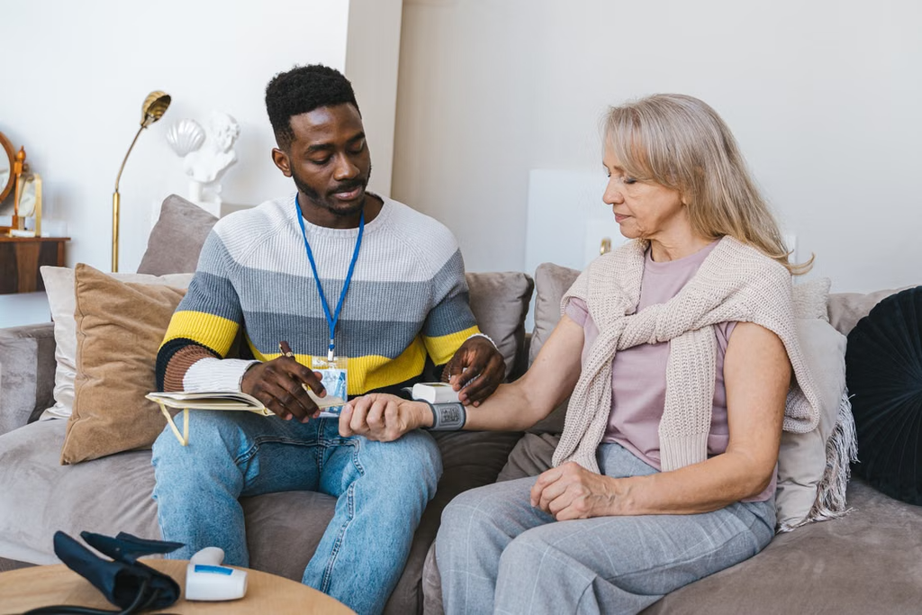 A home healthcare worker checks an older adult’s blood pressure during an in-home care visit.