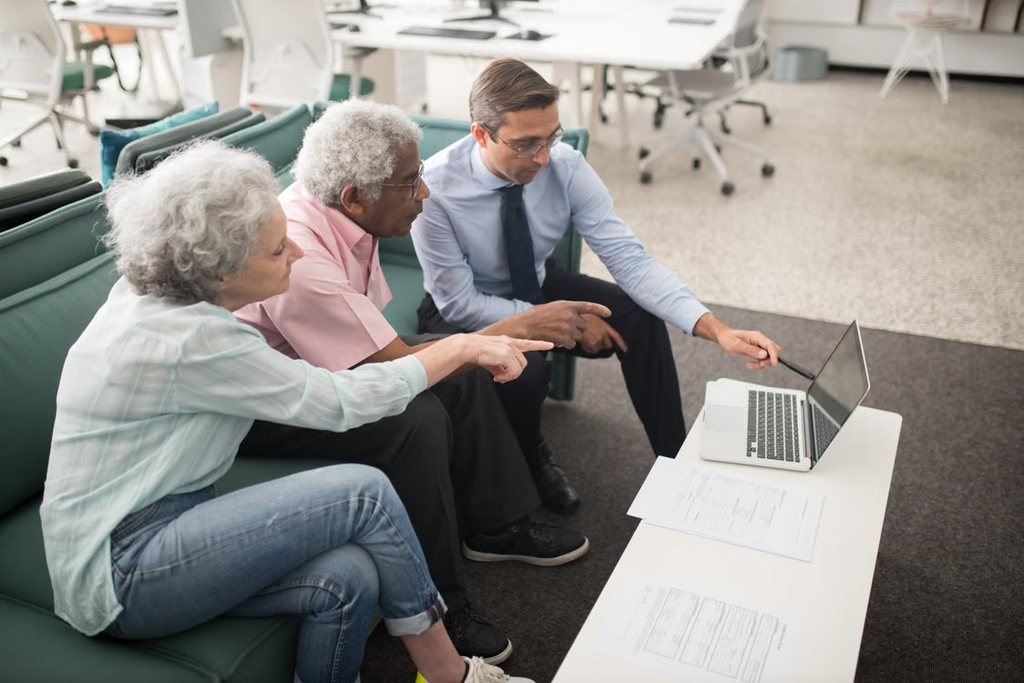  Older couple discussing information on a laptop with a healthcare advisor.